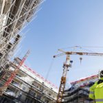Building works, man in high vis jacket standing under a crane