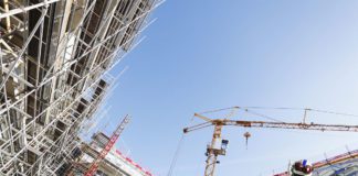 Building works, man in high vis jacket standing under a crane