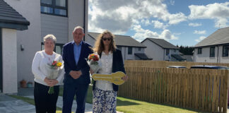 Housing Minister Paul McLennan and two tenants along with a photo of the development