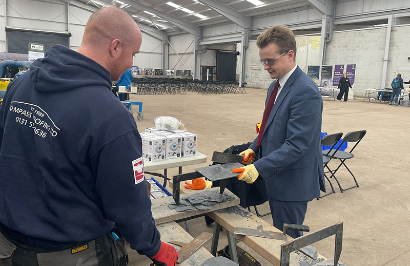 Kyle Stoddart of Compass Roofing Ltd showing MP Euan Stainbank how to cut slate
