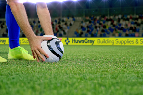 Football match with advertising hoardings in background 