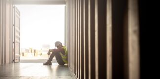 Stressed despair staff in logistic business sittng in container box at shipyard