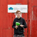 Apprentice Kody Burns in front of HES sign