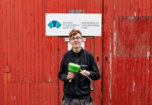 Apprentice Kody Burns in front of HES sign