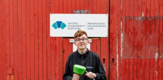 Apprentice Kody Burns in front of HES sign