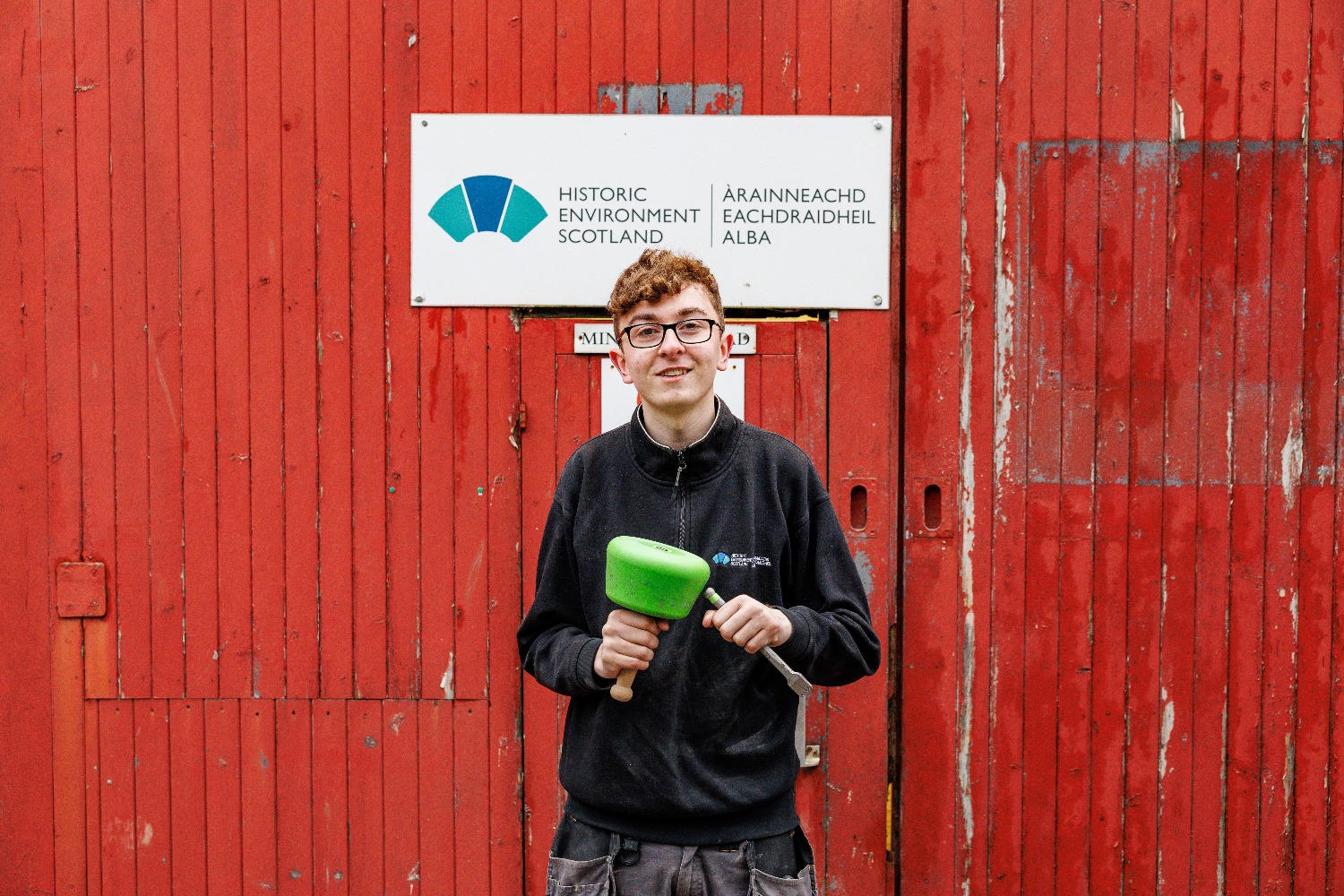 Apprentice Kody Burns in front of HES sign