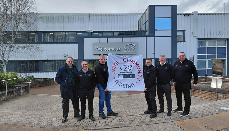 Construction workers holding banner depicting West Highland Way charity trek