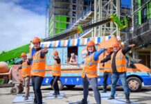 Construction workers participating in yoga session with ice cream truck in background