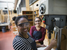 Portrait confident female high school students using drill