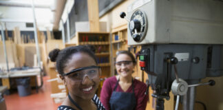 Portrait confident female high school students using drill