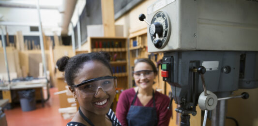 Portrait confident female high school students using drill