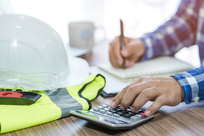 Calculator and construction equipment. Image credit: Shutterstock